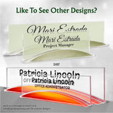 Custom acrylic nameplates shown in two color options: a pale green-tinted clear version with black text reading 'Mari Estrada Project Manager' and an orange-red-tinted clear version with black text reading 'Patricia Lincoln Office Administrator'. The image includes promotional text at the top and bottom.