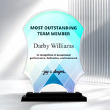 A custom acrylic award plaque on a black base, featuring a blue and white geometric design with the text 'MOST OUTSTANDING TEAM MEMBER Darby Williams' and a signature, set against a modern white background with vertical light bars.