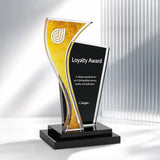 A modern acrylic and glass award trophy with a black base, featuring a gold textured panel and a black front panel engraved with the words 'Loyalty Award' and a small 'C.design' logo, shown on a white background with soft vertical shadows.